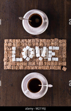 Image conceptuelle sur le thème de la Saint-Valentin . Mot amour faite de sucre brun et blanc et tasses de café . Banque D'Images
