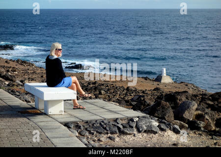 Femme assise sur le banc à Caleta Corcha Concreate entre Caleta de Fuste & Caleta de la recherche sur Fuerteventura dans les Canaries, l'Espagne, l'Union européenne. Banque D'Images