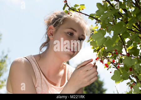 Une jeune femme souriant reprend de Corinthe dans le jardin en été Banque D'Images