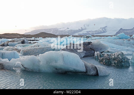 Les icebergs se détachent du glacier Breiðamerkurjökull dans le lagon de Jökulsárlón, en Islande. Vous pouvez voir des couches de cendres volcaniques noirs dans la glace. Banque D'Images