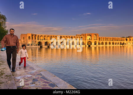 Isfahan, Iran - avril 24, 2017 : un homme à la tête d'un enfant par le bras pour marcher le long de talus de la rivière Zayandeh sur fond de la pierre protect Banque D'Images