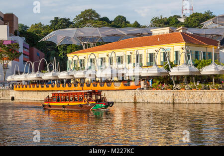 Un voyage rempli de touristes traditionnels moteurs au-delà de Clarke Quay sur la rivière Singapour. Banque D'Images