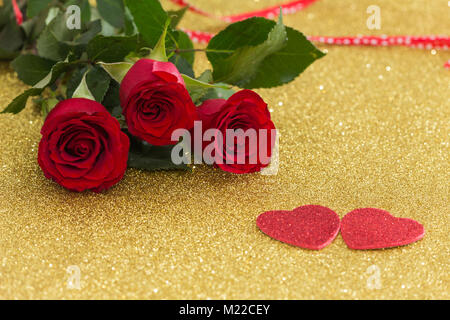 Belles roses rouges avec des coeurs sur un fond d'or Banque D'Images