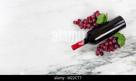 Vue de dessus de la bouteille de vin rouge avec des raisins sur pierre de marbre naturel définition Banque D'Images