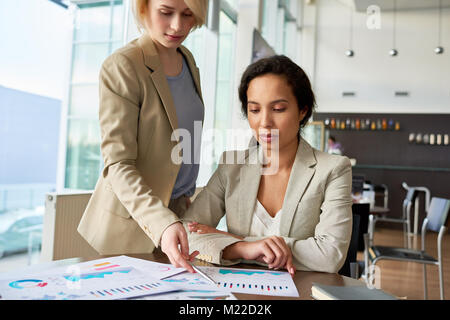 Certains jeunes travailleurs en col blanc en soirée à l'analyse des résultats du travail accompli pendant que se sont réunis à grand open plan office Banque D'Images