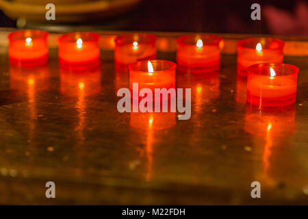 Flammes de bougies votives rouge sur support Banque D'Images