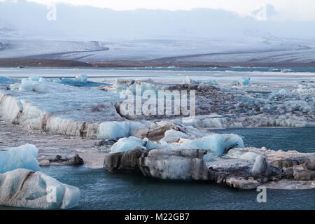 Des icebergs sur la lagune de Jökulsárlón après la rupture du glacier Breiðamerkurjökull de fusion, de l'Islande. Ils ont des couches de cendres volcaniques noires. Banque D'Images