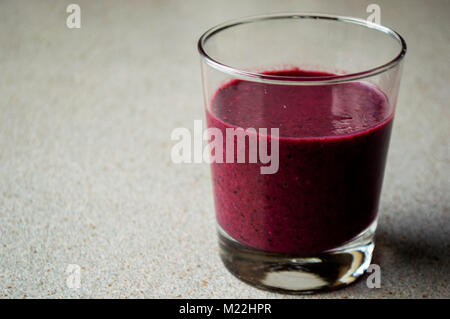 Smoothie violet avec des baies et de fruits en verre sur un tableau gris. Banque D'Images