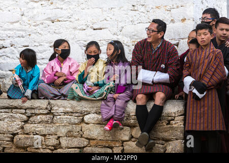 Prakhar Lhakhang, Bumthang, Bhoutan. Les jeunes filles bhoutanais en vêtements traditionnels, avec des masques respiratoires. Les hommes dans les hommes, Gho traditionnel du vêtement. Banque D'Images