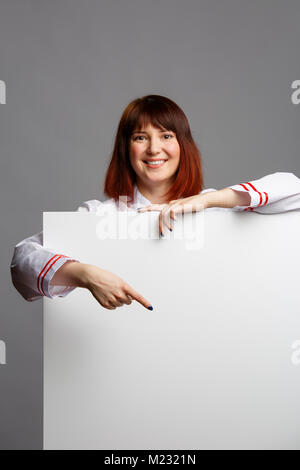 Image femme cuisinière en robe blanche face à la feuille d'inscription vide Banque D'Images