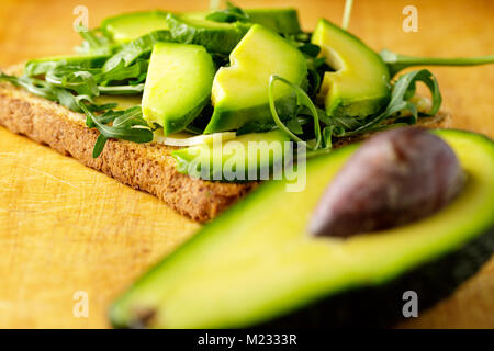 Toast à l'avocat avec rucolla sur table en bois. Banque D'Images