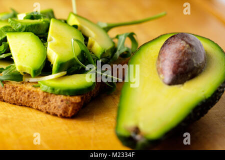 Toast à l'avocat avec rucolla sur table en bois. Banque D'Images