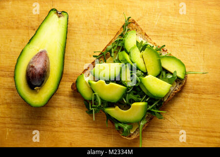 Toast à l'avocat avec rucolla sur table en bois. Banque D'Images