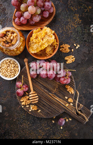 Les raisins, miel et noix sur planche à découper en bois. Banque D'Images