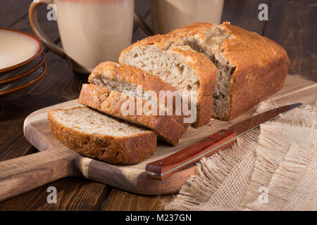 Pain aux noix banane en rondelles sur une planche à découper en bois Banque D'Images