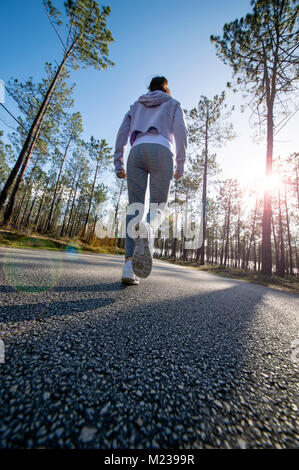 Woman power walking le long d'une route à travers le pays, low angle, des reflets. Banque D'Images