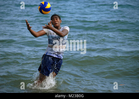 Garçon fidjien jouant avec un ballon de soccer dans la mer, Palm Beach, Fidji. Banque D'Images