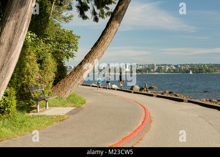 Vancouver, Colombie-Britannique, Canada. Les touristes à pied le chemin sur le Stanley Park Seawall un soir d'été. Banque D'Images