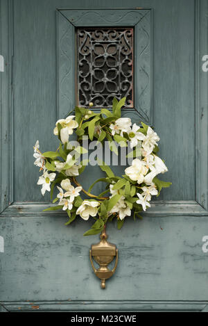 Meubles anciens en bois porte bleue avec guirlande de fleurs artificielles et de laiton knocker Banque D'Images