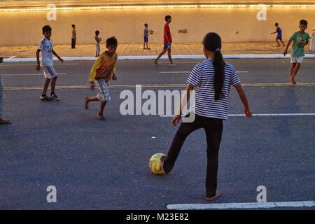 Fille et les enfants cambodgiens sur maison flottante, Kompong Chhnang, Cambodge jouant au football dans l'avant du Palais Royal, Phnom Penh, Cambodge Banque D'Images