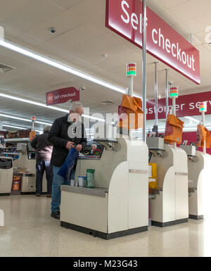 / Hommes âgés de sexe masculin les clients de payer pour leurs achats à l'espace de caisse dans un supermarché Sainsbury's Bourne, Lincolnshire, Angleterre, Royaume-Uni. Banque D'Images