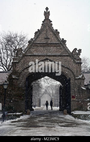 Une légère neige tombe sur les étudiants marchant à travers la porte de Cobb à l'Université de Chicago. Banque D'Images