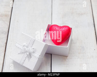 Coeur rouge à l'intérieur de boîte-cadeau blanche sur fond de bois blanc Banque D'Images