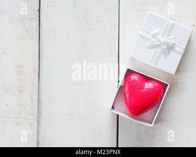 Coeur rouge à l'intérieur de boîte-cadeau blanche sur fond de bois blanc Banque D'Images