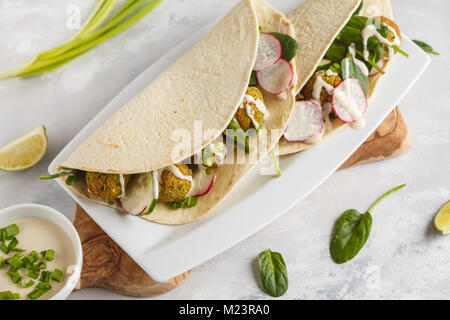 Falafels végétaliens avec légumes et sauce tahini tortilla dans sur un plat blanc. Vegan aliments sains Banque D'Images