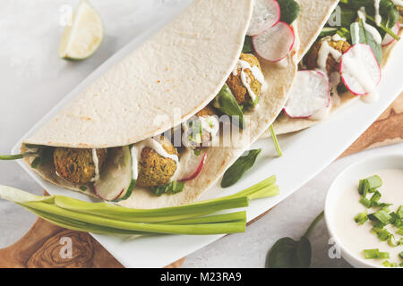 Falafels végétaliens avec légumes et sauce tahini tortilla dans sur un plat blanc. Vegan aliments sains Banque D'Images