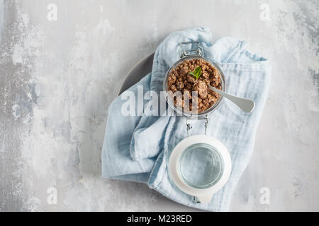 Cuit au chocolat muesli (granola) dans un bocal en verre. Vue de dessus, copiez l'espace, fond gris. Banque D'Images