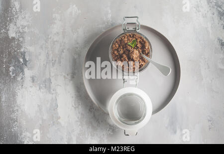 Cuit au chocolat muesli (granola) dans un bocal en verre. Vue de dessus, copiez l'espace, fond gris. Banque D'Images