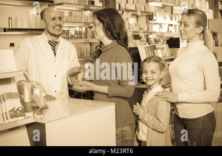 Smiling senior pharmacien debout avec un paiement 24 dans la pharmacie et l'aide aux clients Banque D'Images