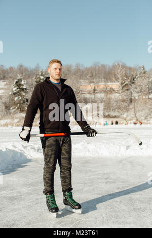 Homme portant des patins à glace tenant un bâton Banque D'Images