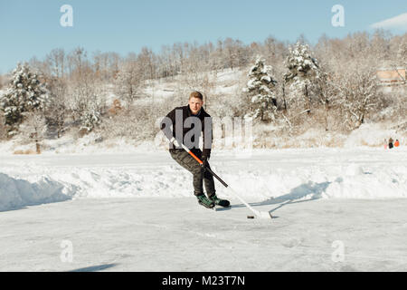 Man playing ice hockey sur un lac gelé Banque D'Images