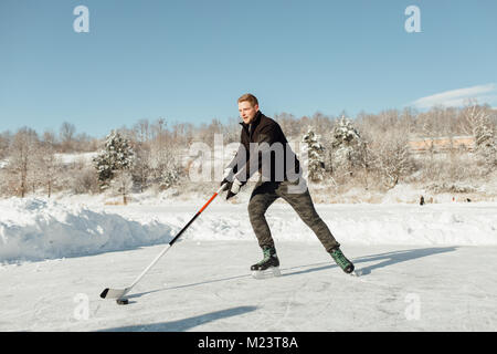 Man playing ice hockey sur un lac gelé Banque D'Images