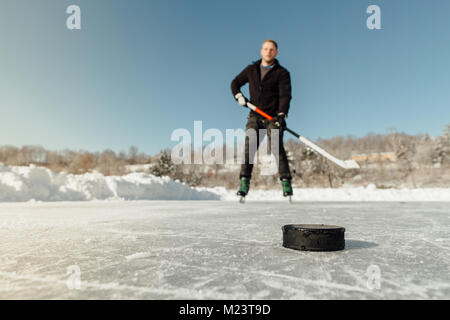 Man playing ice hockey sur un lac gelé en se concentrant sur un puck Banque D'Images