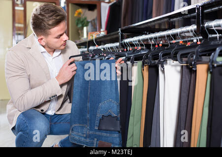 Jeune homme de choisir de nouveaux pantalons en toiles de store Banque D'Images