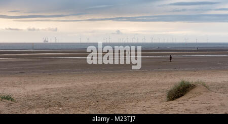 Liverpool, Angleterre, Royaume-Uni - 12 novembre 2016 : Le soleil se couche derrière Antony Gormley est "un autre endroit" sculptures sur Crosby Beach, et des parcs éoliens et la n Banque D'Images