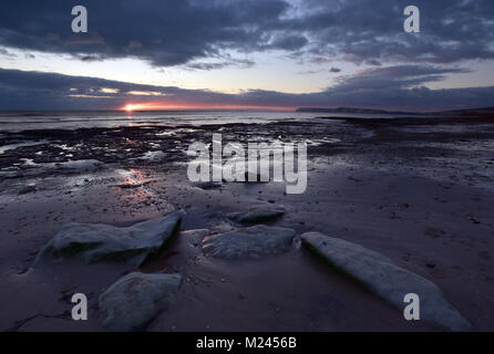 Compton Bay, île de Wight, Royaume-Uni 4 février 2018. L'instabilité et le temps orageux continue de noir et de nuages menaçants dans un ciel orageux et moody sur Compton Bay sur la côte sud-ouest de l'île de Wight. Le soleil qui se reflète dans le sable humide et les rochers sur la plage avec les falaises de la baie d'eau douce dans l'arrière-plan. Crédit : Steve Hawkins Photography/Alamy Live News Banque D'Images