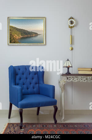 Mobilier Vintage - Intérieur composition du fauteuil bleu retro vintage beige en bois, table, lampe de table, livres, et horloge à pendule au mur blanc Banque D'Images