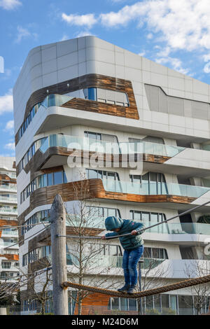 Petit garçon 4-6 ans joue sur une corde raide dans une aire de jeux dans le Tre Torri du district Citylife de Milan, Italie au cours d'une journée d'hiver ensoleillée Banque D'Images