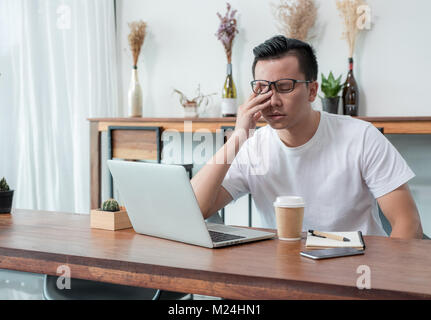 Asie casual man couvrir le visage avec la main en colère de travailler en face de l'ordinateur portable dans un café,émotion,stress concept travailler à l'extérieur, travailler à la maison Banque D'Images