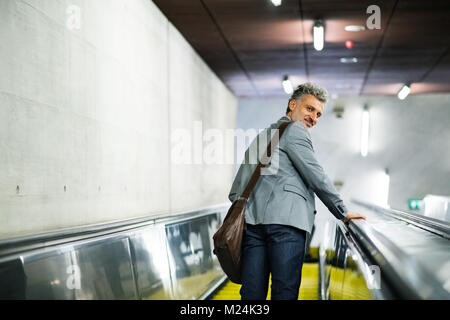 Homme d'affaires sur un escalator sur une station de métro. Banque D'Images