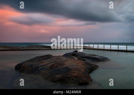 North Curl Curl rockpool photographié lors d'un coucher de soleil orageux. Sydney, plages du nord, de l'Australie. Banque D'Images