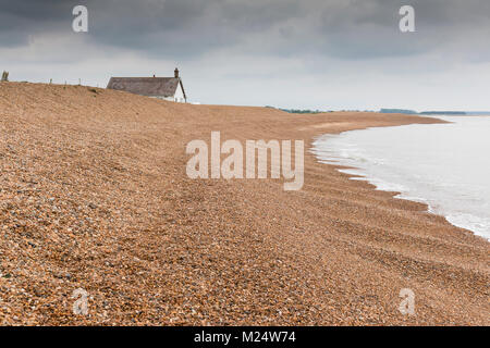 L'image d'une maison solitaire par la mer, avec une plage de galets en pente vers l'eau à Shingle Street, Suffolk, Angleterre, RU Banque D'Images