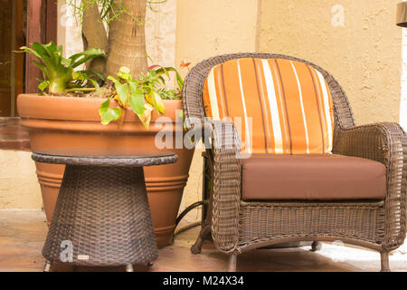 Wicker chaise avec coussin à rayures orange et semoir en terre cuite Banque D'Images