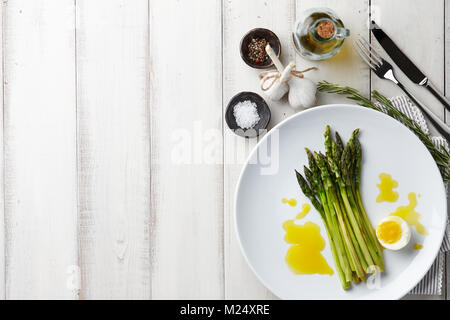Asperges au four avec oeuf mollet en grande plaque blanche sur fond de pierre, vue du dessus Banque D'Images