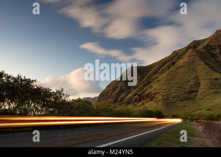 Les sentiers de la lumière des voitures roulant vers le bas la route 93 dans la région de Makaha Valley dans Oahu, Hawaii Banque D'Images