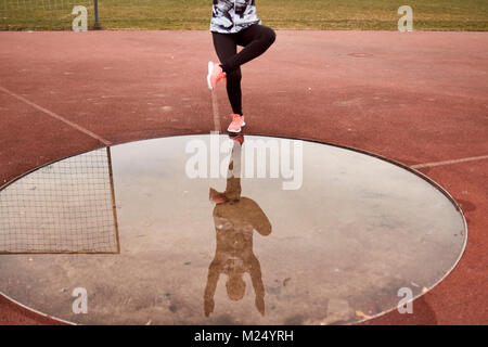 L'exercice d'une personne, vêtements de sport, collants, mare la réflexion dans l'eau, de l'accroupissement Single-Leg Banque D'Images